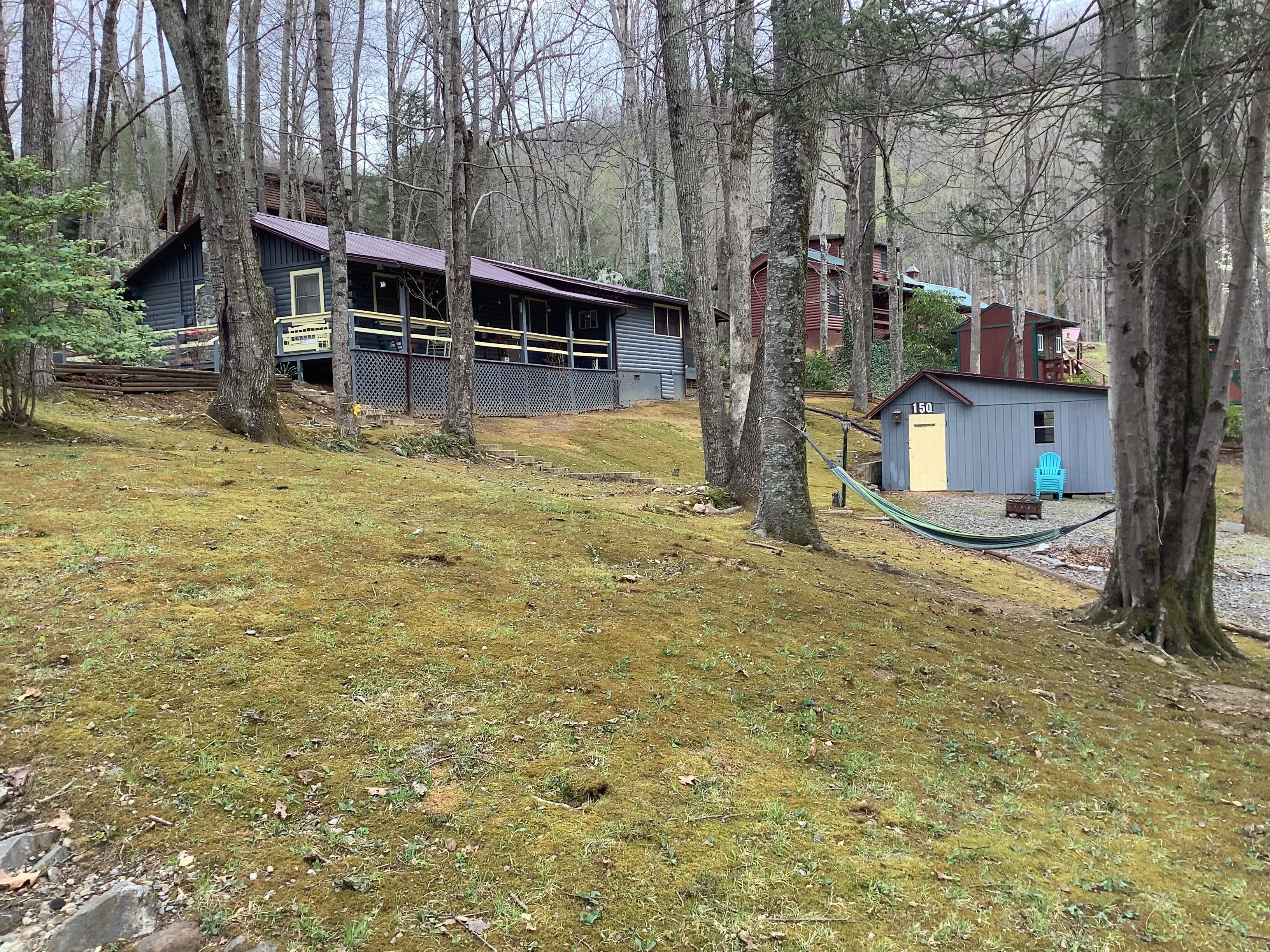Une cabane rustique dotée d’une terrasse en bois et d’un petit abri de jardin.