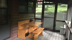 A wooden bench and table set on a porch with a view of a grassy area. -  Pet friendly , Motorcycle parking  Hot tub. Close to everything (Maggie Valley)