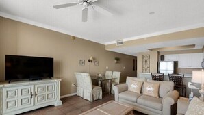 A living room with a television, a sofa, a coffee table, and a dining area with chairs and a table.