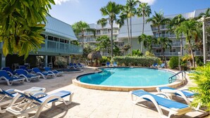 A pool area with lounge chairs and a building with balconies.