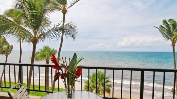 A balcony with a glass table and chairs, overlooking a beach with palm trees and the ocean. - OceanFRONT, UPDATED, 4th Floor, 1BR Cali King, Non-Smoking, SHARP! (Kihei)