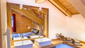 Een moderne badkamer met een grote spiegel, twee wasbakken en houten balken.