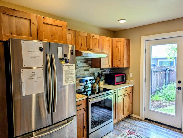 A kitchen with wooden cabinets, stainless steel appliances, a microwave, and a door leading to a backyard.