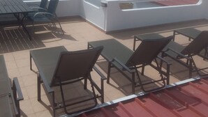 A rooftop terrace with lounge chairs and a table, overlooking a beach. - Beach House in a fantastic location With Stunning Views.  (algarve)