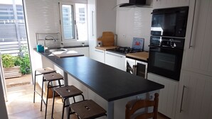 A modern kitchen with a long island, bar stools, a gas stove, and a built-in oven. - Beach House in a fantastic location With Stunning Views.  (algarve)
