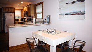 Una cocina moderna con armarios de madera, una isla central y un comedor con mesa y sillas.