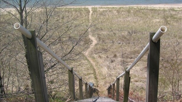 Una escalera de madera que lleva a una playa con vista despejada al océano.