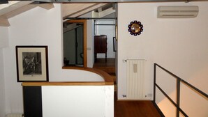 Una escalera con barandilla de madera, un radiador y un cuadro enmarcado en la pared.