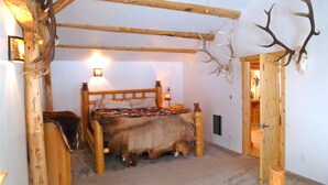 A rustic room with a wooden bed, antler decorations, and a bear skin rug. - Peacful and cozy cottage in the mountains (Bigfork)
