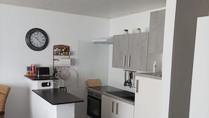 A compact kitchen with a central island, a built-in oven, and white cabinetry.