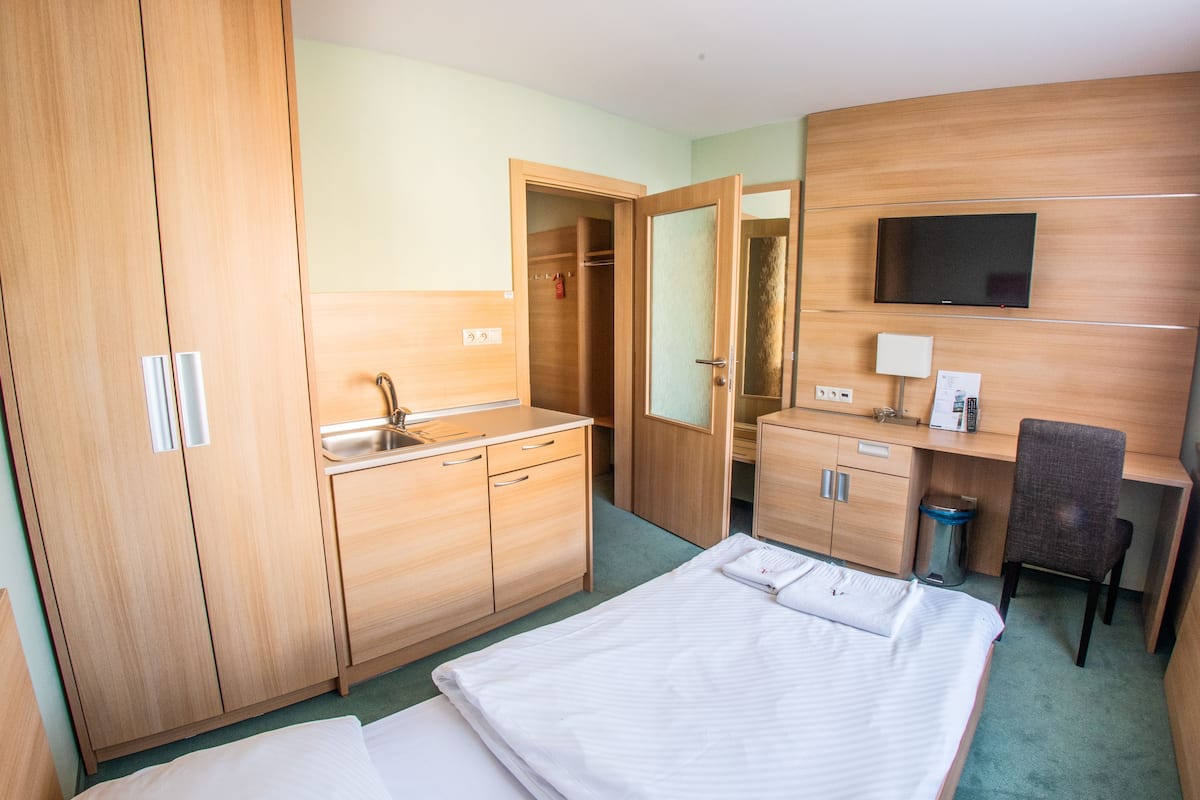 A hotel room with a bed, a desk, a chair, a TV, a wardrobe, and a bathroom.