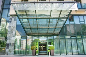 The exterior of the Alexandra Hotel with a modern glass facade, a covered entrance, and a visible entrance door. - Alexandra Business Hotel (Puchov)