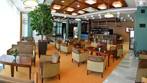 Um hall amplo com várias áreas de estar, um bar e uma grande árvore.
