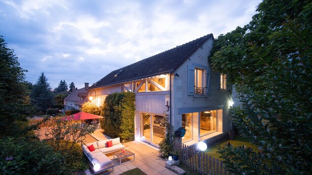 A two-story house with a patio area, a red umbrella, and a white sofa. - Le Clos de La Rousselière B&B (Francueil)