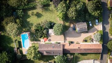 Ovenfra ses et boligområde med en swimmingpool, flere huse og en vej.