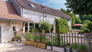 A two-story house with a sloped roof, a wooden fence, and a gravel driveway. - Le Clos de La Rousselière B&B (Francueil)