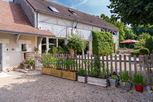 Une maison à deux étages avec un toit en pente, une clôture en bois et une allée gravillonnée.