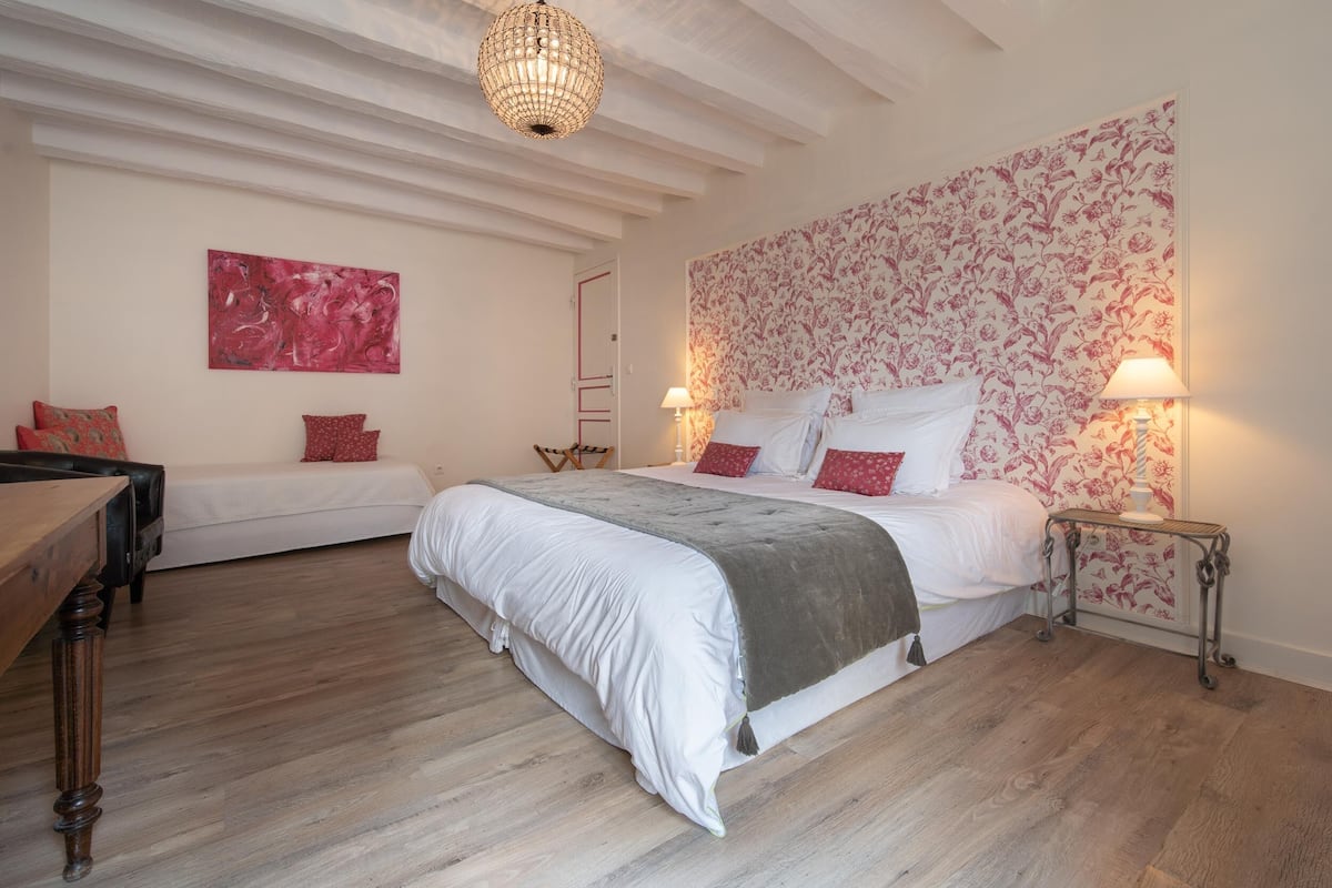 Ein Schlafzimmer mit einem großen Bett, einer kleineren Couch, einem Holztisch und einer Kristallleuchter.