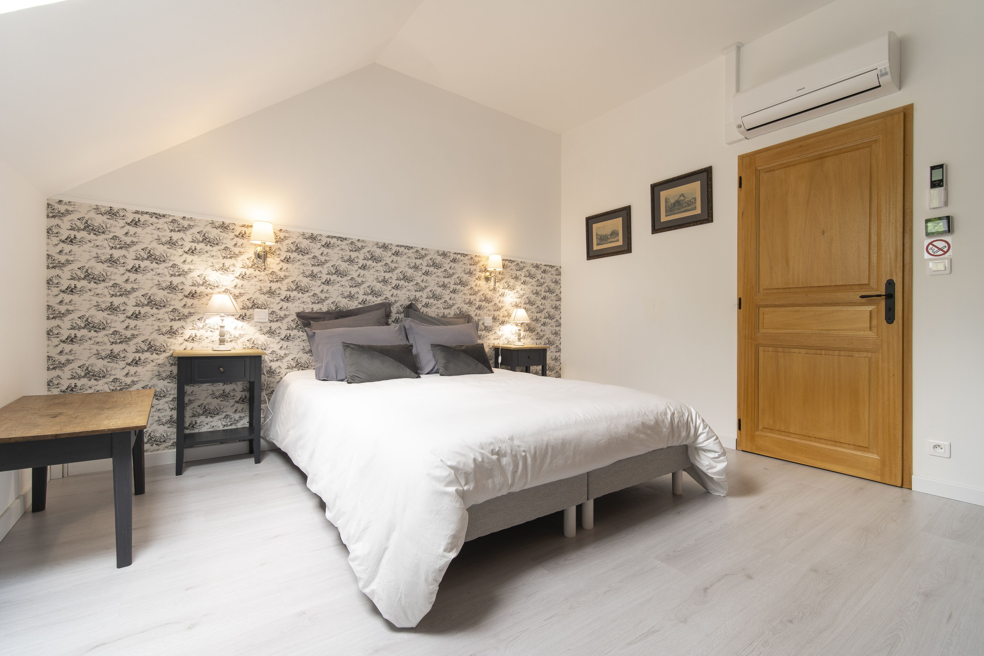 Un dormitorio con cama, mesitas de noche, un escritorio y una puerta de madera.