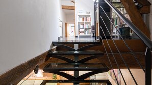 A modern staircase with glass railings and wooden accents, leading to a dining area with a table and chairs. - Le Clos de La Rousselière B&B (Francueil)