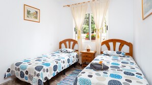 A bedroom with two single beds, a wooden nightstand, a bedside table with a lamp, and a window with curtains. - Finca La Gaviota - Los Limoneros (Icod de los Vinos)