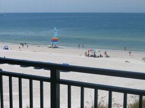 A beach with a sailboat, people, and beach umbrellas. - Luxury Gulf Front Condo on St. Pete Beach  Spectacular Sunsets & Views (St. Pete Beach)