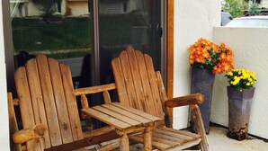 Une chaise Adirondack en bois est placée à l’extérieur d’un bâtiment doté d’une porte-fenêtre coulissante.