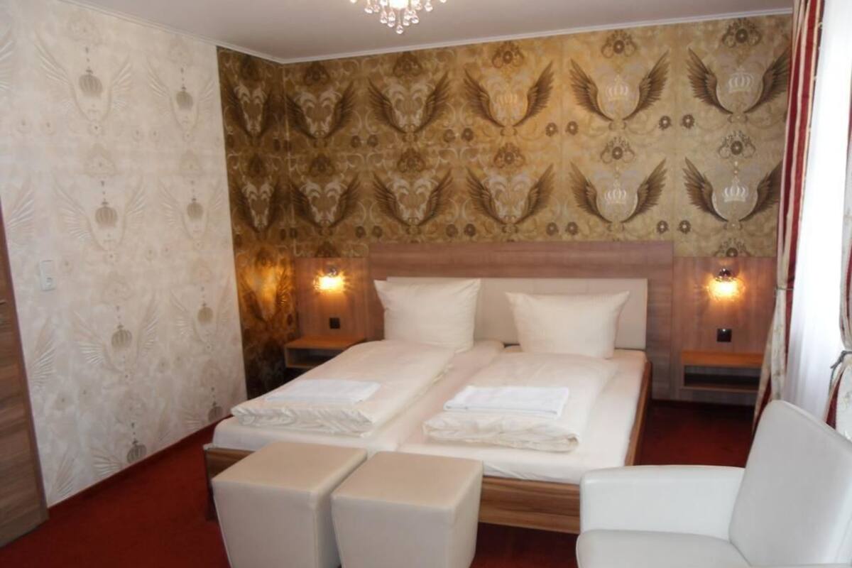 A hotel room with a large bed, two bedside tables, a chair, and a red carpet.