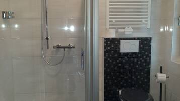 Un baño moderno con ducha envuelta en vidrio, inodoro y lavamanos.