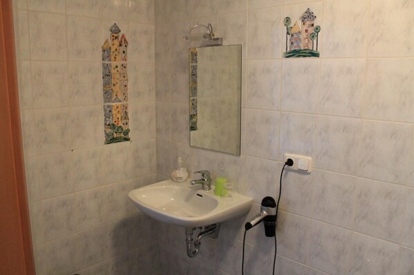 A bathroom with a white sink, a mirror, and decorative tiles on the walls.