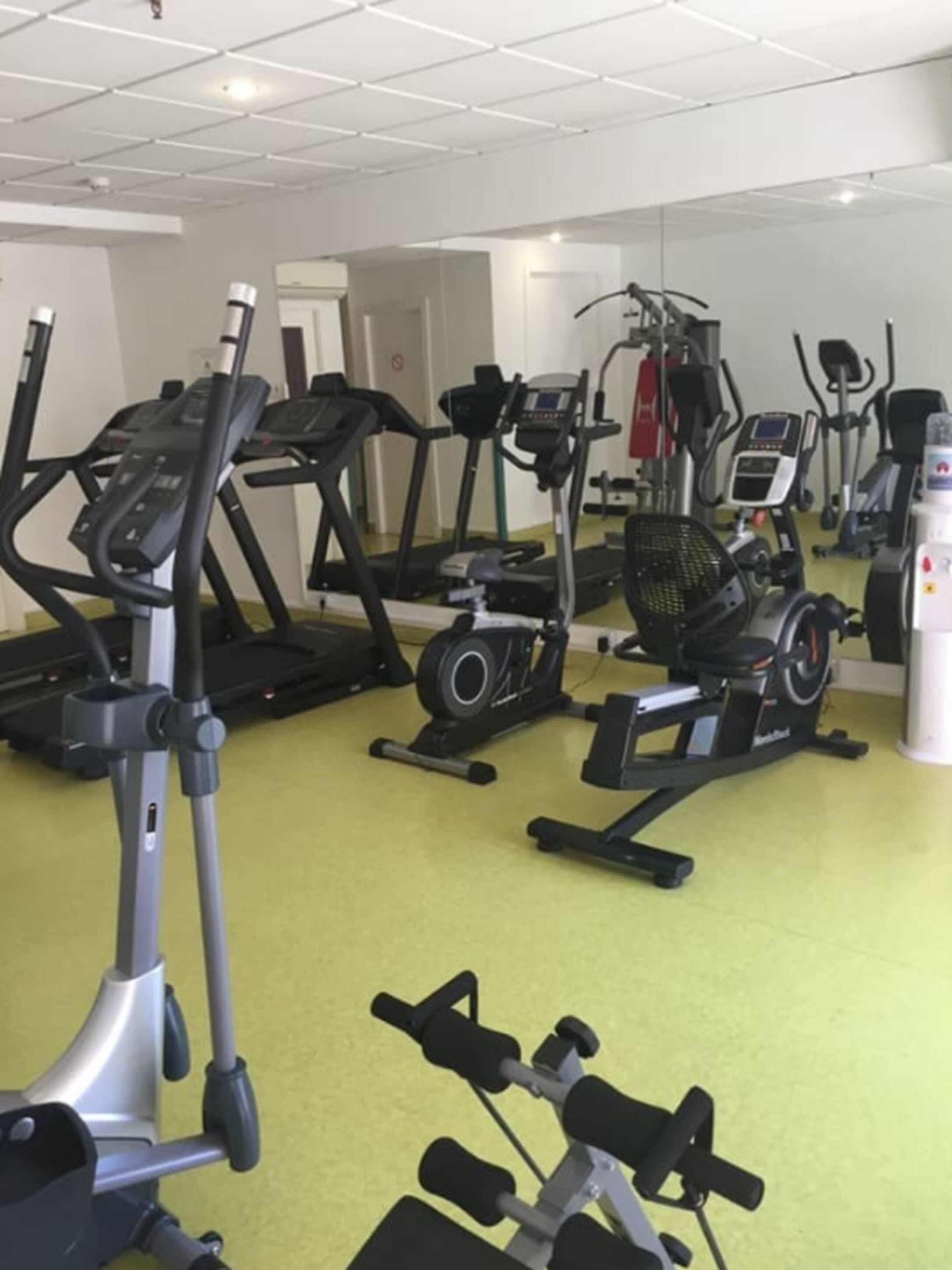 A gym with various exercise equipment including treadmills, elliptical machines, and weight benches.