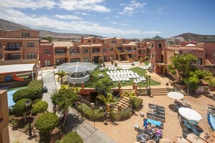 A resort with multiple buildings, a swimming pool, and sun loungers.