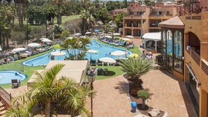 A resort with multiple swimming pools, palm trees, and a mountainous backdrop. - Hotel Villa Mandi Golf Resort (Arona)