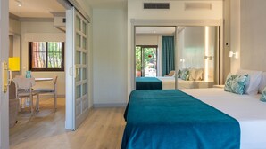 A hotel room with a bed, a desk, and a chair. There is a window with a view of the outside. - Hotel Villa Mandi Golf Resort (Arona)