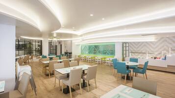 Een moderne eetruimte met tafels en stoelen, een toonbank met presentatie en een behang met patroon.