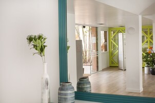 A modern interior with a hallway leading to a bright room with a green accent wall and a staircase.