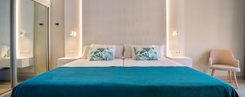 Una habitación de hotel moderna con una cama grande, dos mesitas de noche, una silla y un espejo.