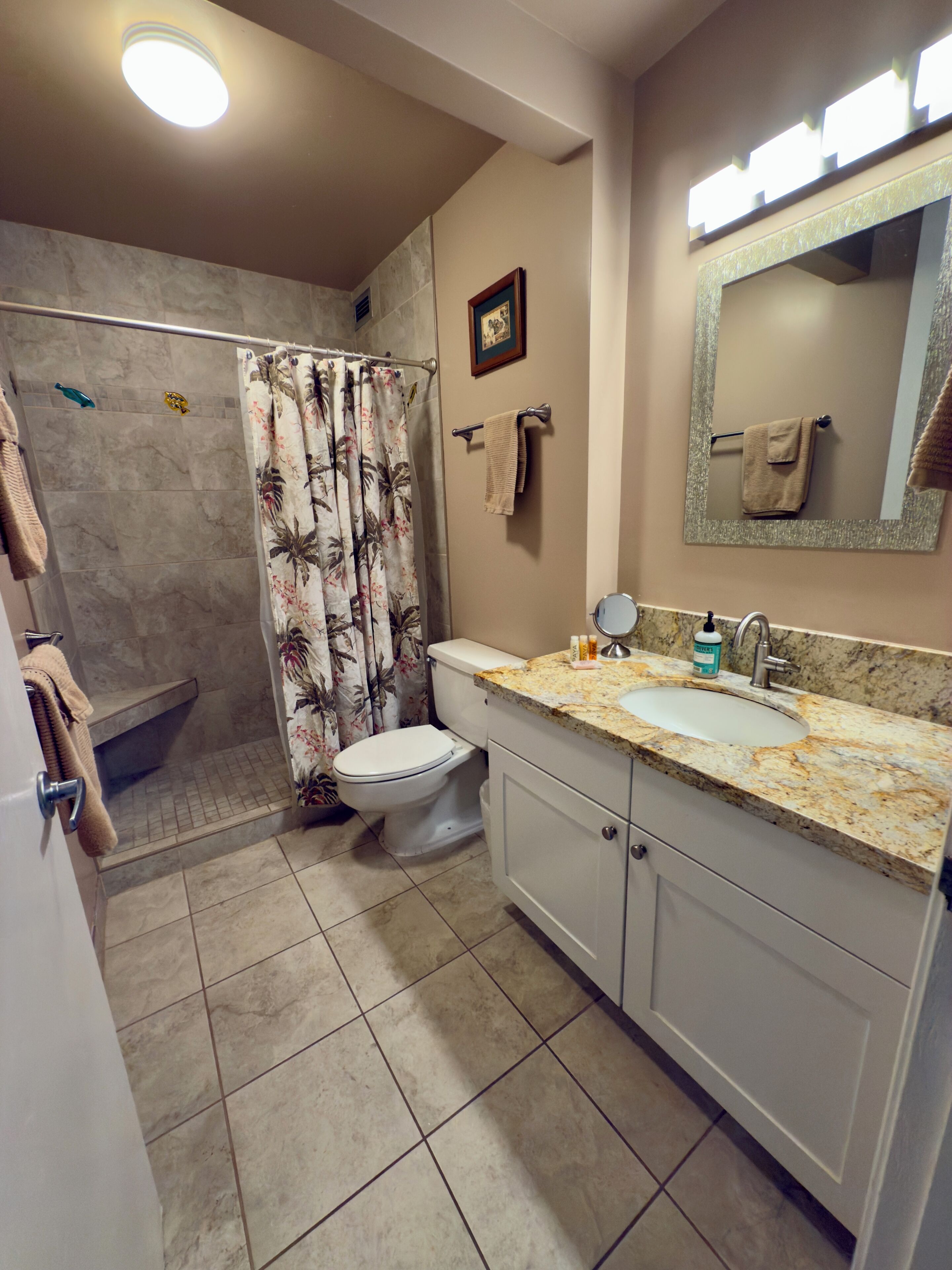 Une salle de bain équipée d’une douche, de toilettes, d’un lavabo et d’un miroir.