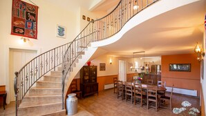 Un amplio espacio habitable con una escalera curva, una mesa de comedor y una zona de cocina.