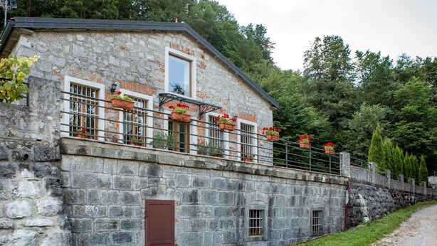 Un edificio de piedra con un balcón, una puerta y una ventana.