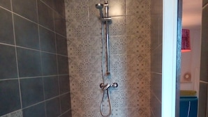 Casa de banho com chuveiro, lavatório e azulejos estampados.