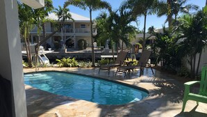 A swimming pool with a tiled deck, surrounded by palm trees and lounge chairs.