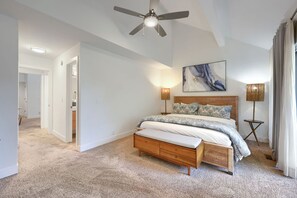 Een slaapkamer met een bed, nachtlampen, een plafondventilator en een schilderij aan de muur.
