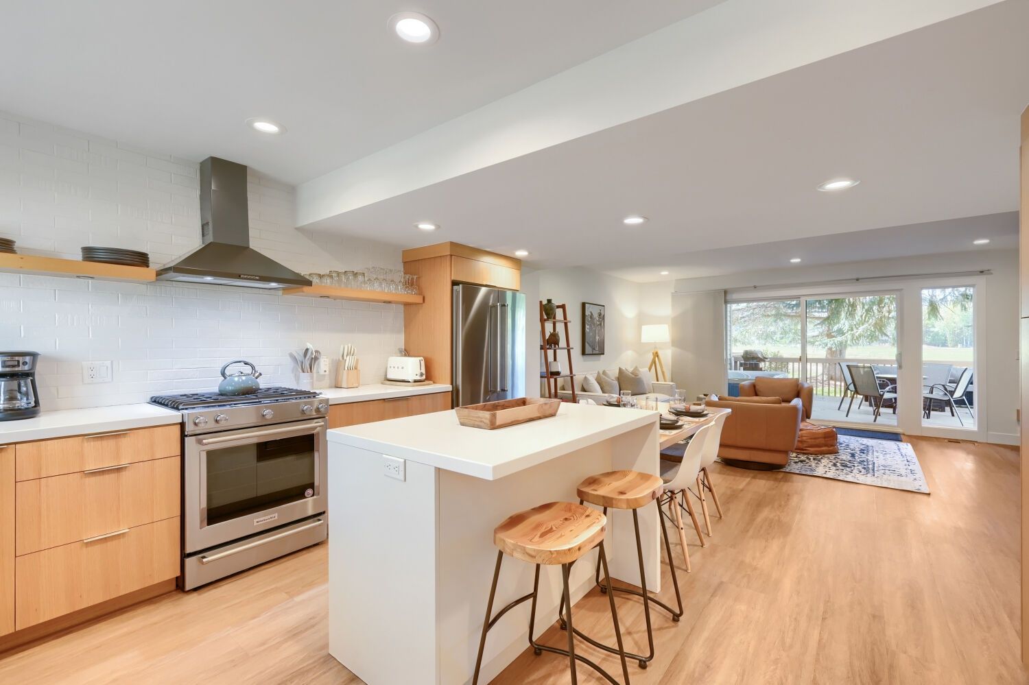 Una cocina moderna con una isla central, electrodomésticos de acero inoxidable y una zona de comedor con sofá y sillas.