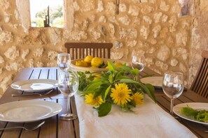 A table set for two with plates, cutlery, and glasses, and a vase with yellow flowers. - Typical country property with Yacuzzi pool and large outdoor area (Porreres)
