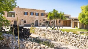 A stone building with a tiled roof, a paved courtyard, and a stone wall. - Typical country property with Yacuzzi pool and large outdoor area (Porreres)