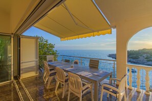 A terrace with a table and chairs, overlooking the sea.