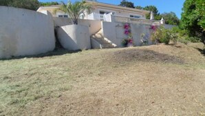 A house with a white exterior, a small garden with a palm tree, and a white fence. - Superb infinity pool villa with stunning sea views in Favone  (Sari-Solenzara)