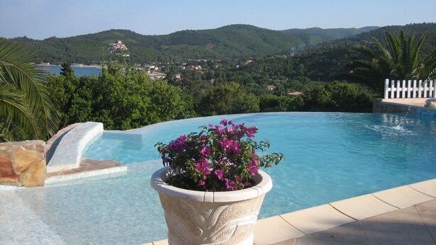 A swimming pool with a view of a coastal town and hills in the background. - Superb infinity pool villa with stunning sea views in Favone  (Sari-Solenzara)