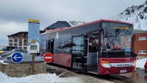 A red bus parked in a snowy area with a mountain in the background. - La Mongie 2 rooms 4 persons Residence Pic du Midi parking and swimming pool (Bagnères-De-Bigorre)